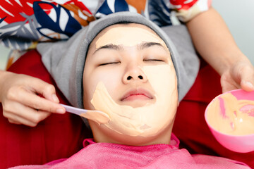 Obraz na płótnie Canvas Beautiful young Asian woman getting a facial mask treatment at the beauty salon. Facial skincare.