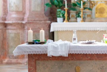 altar with candles, holy water and white dress for babtism - obrazy, fototapety, plakaty