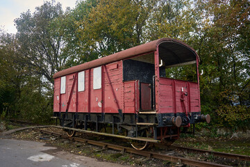 Obraz premium Prestongrange Museum. A vivid red train car sits motionless on train tracks, contrasting with the environment. The tracks extend into the distance, emphasizing their presence.