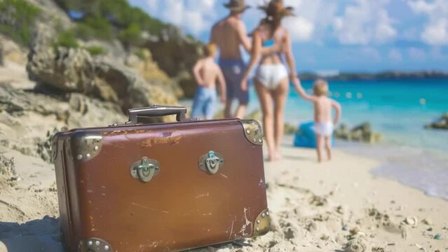 Family summer vacation concept. Suitcase on the beach with happy family on background.

