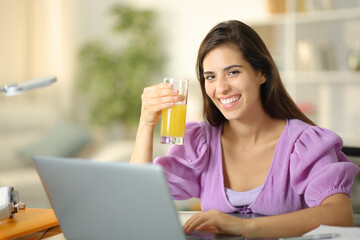 Happy student holding orange juice at home