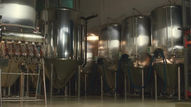 No people panning shot of huge stainless-steel brewing tanks and equipment at manufacturing beer factory