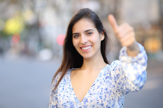 Portrait of a happy woman gesturing thumbs up in the street