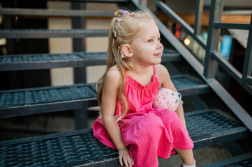 Child girl with hearing aid and cochlear implantation system. Kid with hearing problems walks...
