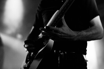 Closeup of a musician playing electric guitar during a concert shot in grayscale