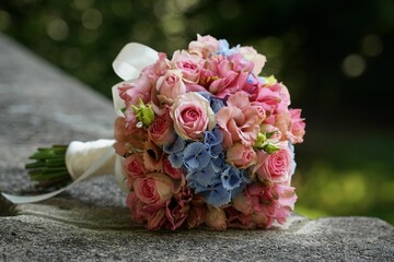 Closeup of a beautiful bouquet of pink and blue flowers on a rock