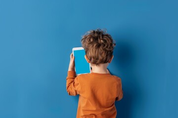 App mockup shoulder view of a boy holding an ebook with an entirely blue screen