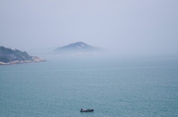 Boat sailing against a misty seascape