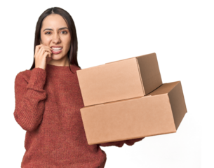 Caucasian young woman with moving boxes on studio background biting fingernails, nervous and very anxious.