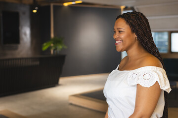 A young biracial woman wearing white is smiling, with copy space