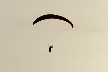 Silhouette of a paraglider against a light sky