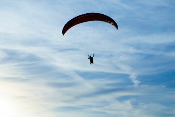 Cloudy blue sky with a silhouette of a paraglider