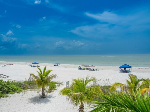 People resting on a sandy beach on a cloudy day in Estero Island, Florida