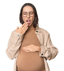 Pregnant young Caucasian woman showcasing maternity on studio background yawning showing a tired gesture covering mouth with hand.
