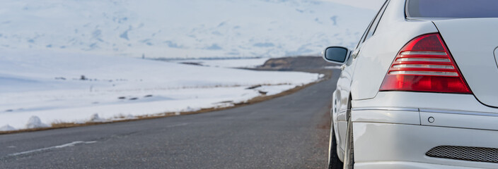 White car on asphalt road in winter, winter travel