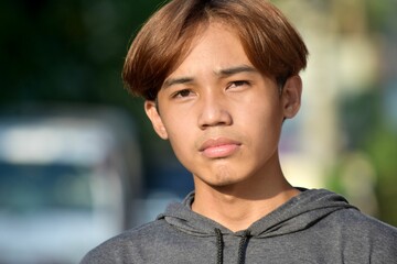 Portrait of a teenage Southeast Asian boy with brown hair in the street