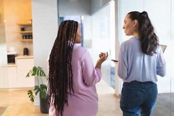 Two women are talking in a modern business office environment
