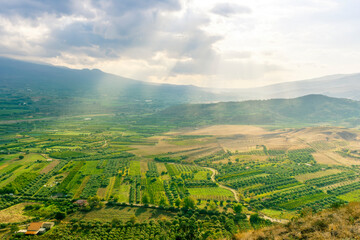 scenic rustic landscape with green hills and farms in a mountain valley during colorful cloudy sunset