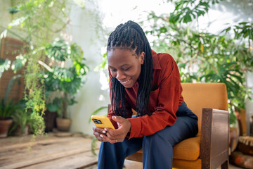Satisfied contented african american woman smiling looking on screen smartphone enjoy online...