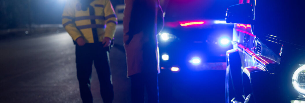 police officer stands next to a car he pulled over for speeding, reaching for the driver's ID,  stock photo