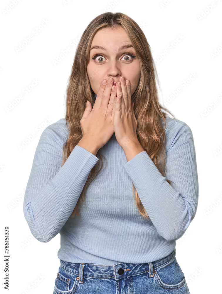 Wall mural Studio portrait of a blonde Caucasian woman shocked, covering mouth with hands, anxious to discover something new. - Wall murals