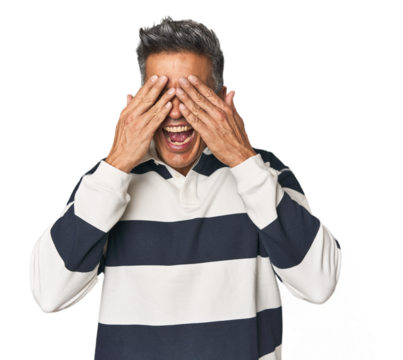 Middle-aged Latino man covers eyes with hands, smiles broadly waiting for a surprise. - Powered by Adobe