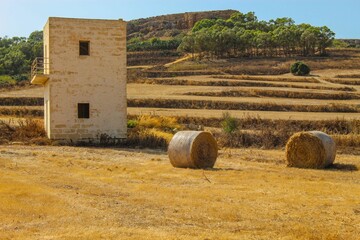Wide shot of a farm house with hay in a field in Malta
