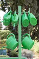 Plastic green watering jugs hang on a metal rack for use by visitors to the Mount Herzl military...