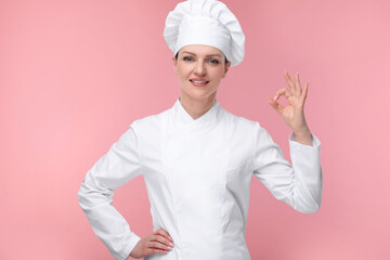 Happy chef in uniform showing OK gesture on pink background