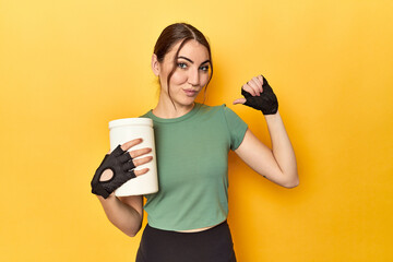 Fit woman holding a protein shake feels proud and self confident, example to follow.