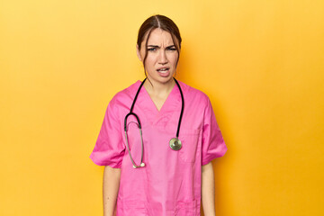 Nursing assistant in yellow background screaming very angry and aggressive.