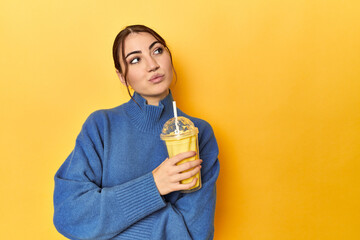 Young caucasian woman enjoying a creamy vanilla shake looking sideways with doubtful and skeptical...