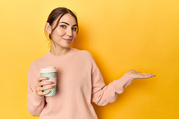 Young caucasian woman holding a takeaway coffee cup showing a copy space on a palm and holding...