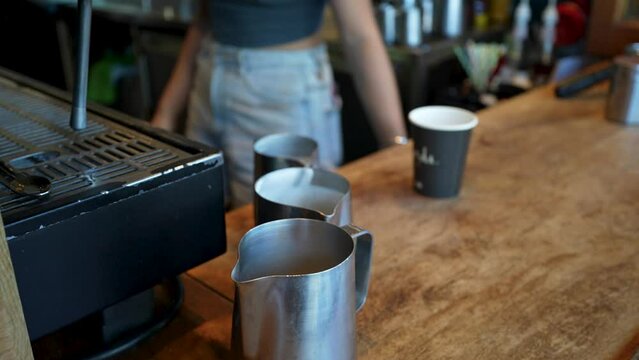 Close-up slow-motion view of a female bartender heating milk for cappuccino