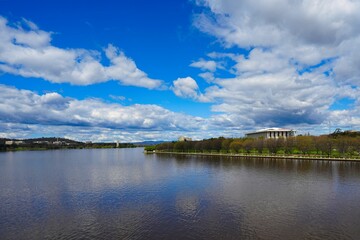 Scenic view of Lake Burley Griffin with row of trees on the shore under blue cloudy sky in Canberra