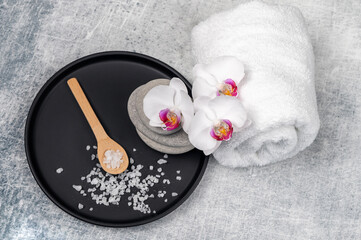 Spa decoration with gorgeous orchid flowers in white and cyclamen, spa stones and rolled towel on...