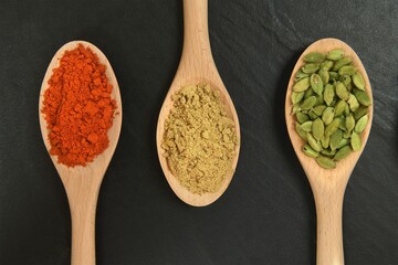 Closeup shot of wooden spoons with different spices - obrazy, fototapety, plakaty