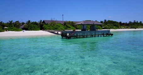 Aerial view of covered jetty on sea surrounded by emerald water in background of growing trees