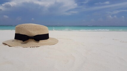 Obraz na płótnie Canvas Closeup shot of sun hat on sandy beach in background of sea