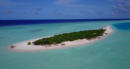 Aerial view of island surrounded by emerald water in Maldives