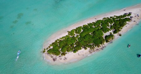 Aerial view of island surrounded by emerald water in Maldives