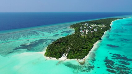 Aerial view of island surrounded by emerald water in Maldives