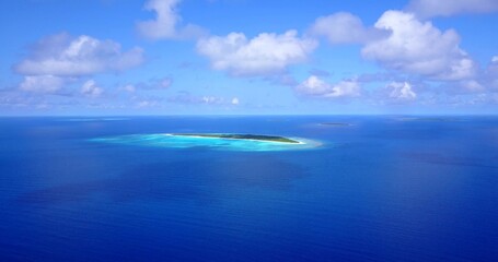 Aerial drone shot of an untouched island in the Maldives washed by the Indian Ocean