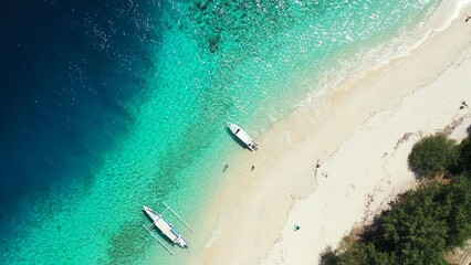 Aerial drone shot of a sandy beach with two boats washed by the Indian Ocean