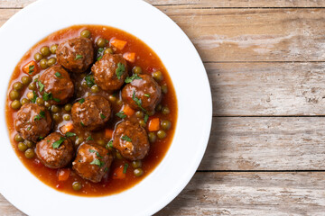 Meatballs, green peas and carrot with tomato sauce on wooden table. Top view. Copy space