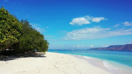 Scenic view of an island covered with greenery against a turquoise sea on a sunny day
