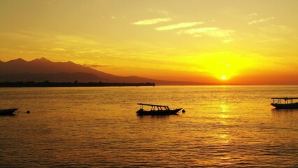 Obraz premium Beautiful view of boats in a sea under the clear sky during sunset in Asia