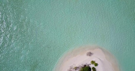 Aerial shot of clear ocean water covering the white sandy beach