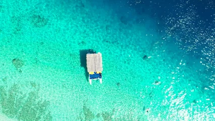 Rolgordijnen Aerial view of floating boat in turquoise ocean © Wirestock