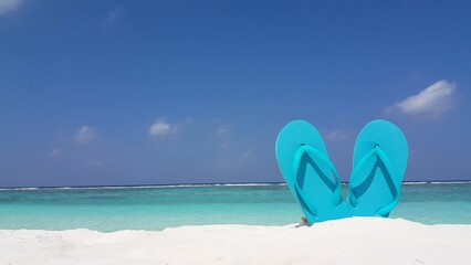 Blue flip flops on a sandy beach